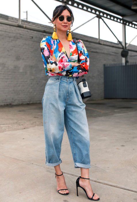 Outfit de mujer con pantalón mom fit azul con blusa de colores, zapatillas y bolso vintage. 