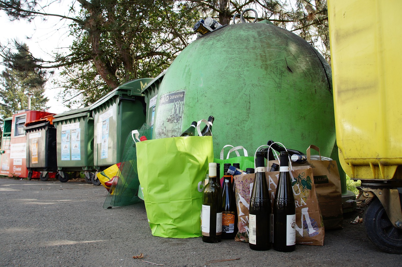Bolsas de bCuatro bolsas llenas de botellas de champagne junto a contenedores de basura de color verde