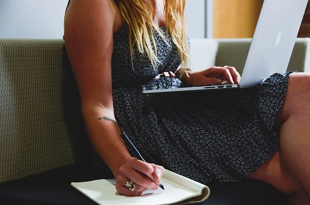 Mujer sentada con laptop en las piernas y escribiendo